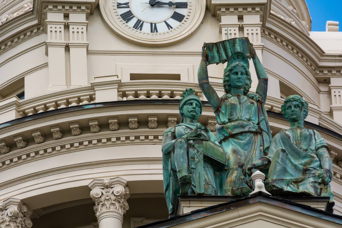 A statue of three individuals in front of a grand building in Troy, OH