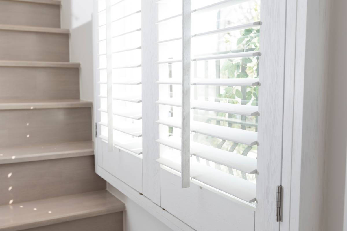 why-choose-custom-shutters-1200px Up-close image of white custom interior shutters in a residential home next to stairs at Signature Shutters & Decor near Moraine, OH