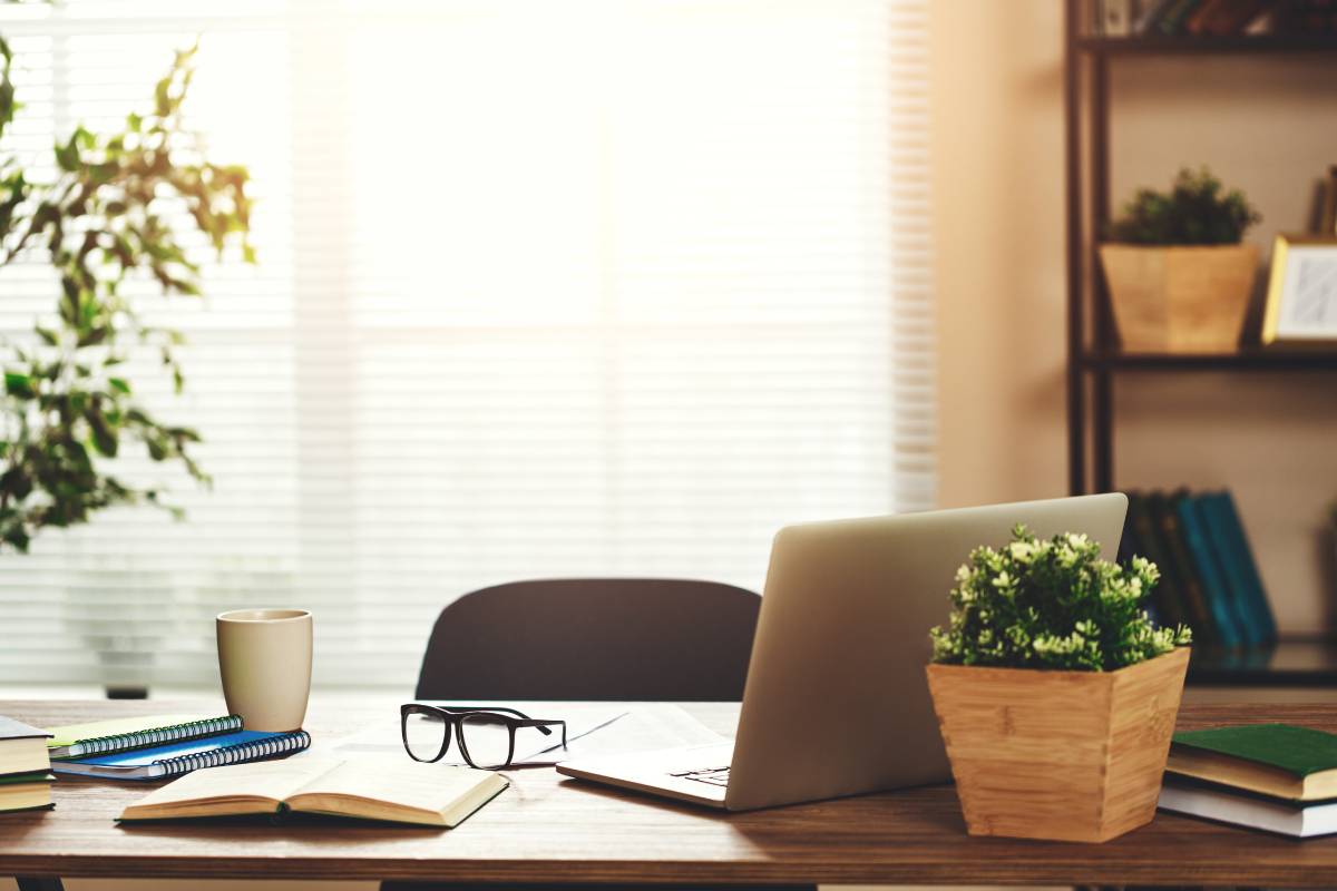 update-your-home-office-with-new-window-treatments-1200px A home office with a busy desk and a large window adorned with blinds at Signature Shutters & Decor near Moraine, OH