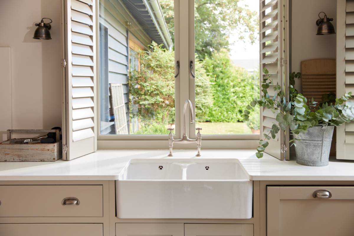 Interior shutters on a window above a kitchen sink featuring rustic interior design style decor at Signature Shutters and Blinds near Moraine, OH