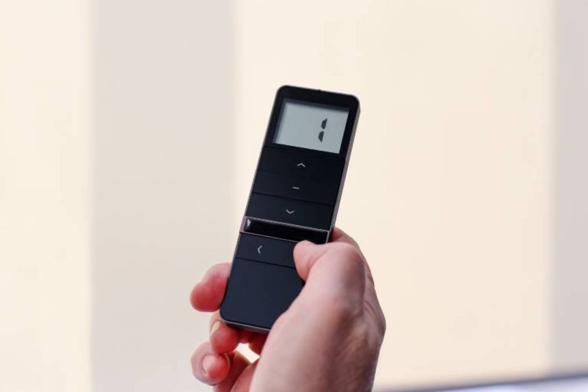 A person who is holding a remote control to operate their motorized shades from Graber®