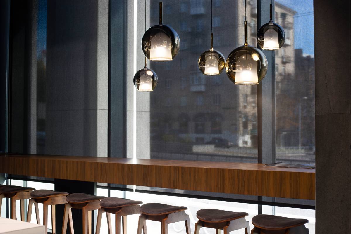 Commercial window shades on a large window with modern light fixtures in a trendy restaurant
