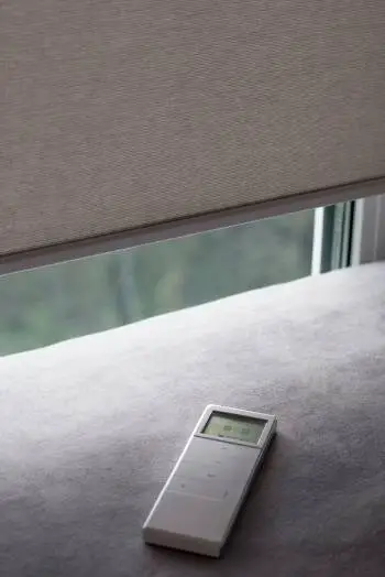 white-remote-control-panel-for-motorized-roller-shades-lies-on-a-sofa | Signature Shutters and Blinds White remote control panel for motorized roller shades lies on a sofa near Dayton, OH