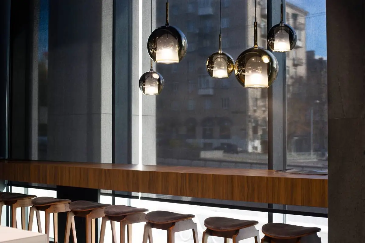 commercial-window-shades-on-a-large-window-with-modern-light-fixtures-in-a-trendy-restaurant-1200px | Signature Shutters and Blinds Commercial window shades on a large window with modern light fixtures in a trendy restaurant